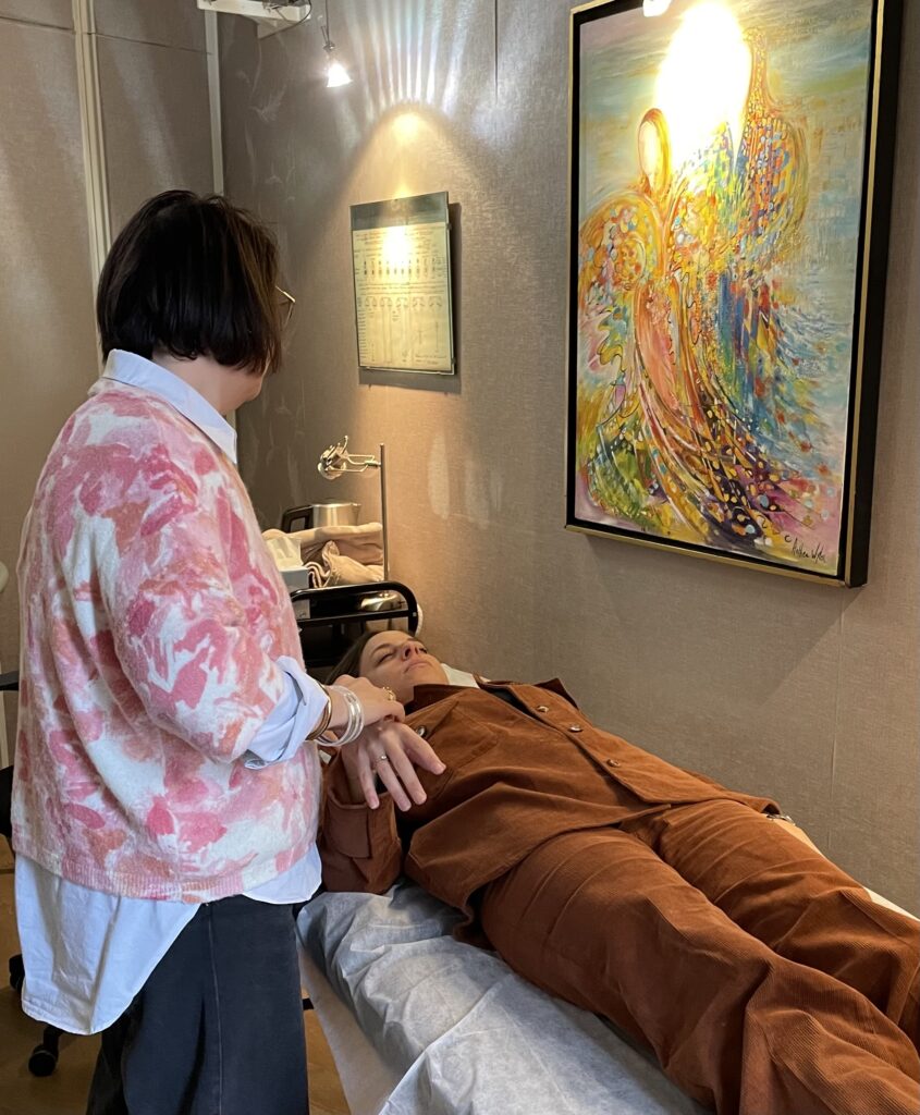 Cabinet de kinésiologue à Paris 6, avec une praticienne qui effectue un test musculaire sur sa cliente allongée.